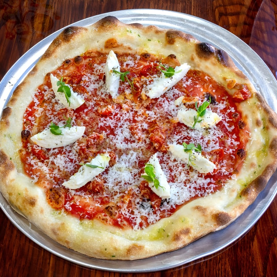 One World Pizza's Margherita pizza with fresh mozzarella, tomato sauce, parmesan, and microgreens.