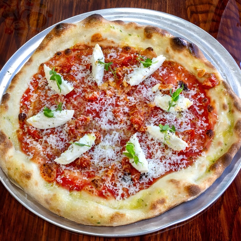 One World Pizza's Margherita pizza with fresh mozzarella, tomato sauce, parmesan, and microgreens.